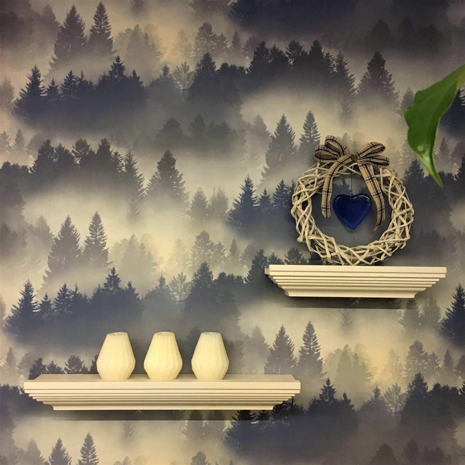 Kuva puodilta: Tauluhyllyt, Kranssi Lasisydän ja Timanttikynttilät, taustalla sinisävyinen maisematapetti.